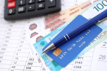 Credit card and pen with russian ruble currency money bills banknotes on calculations document background. Business, financial operations and accounting in Russian Federation