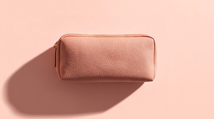 Obraz premium A textured pink cosmetic bag lies flat on a pink surface