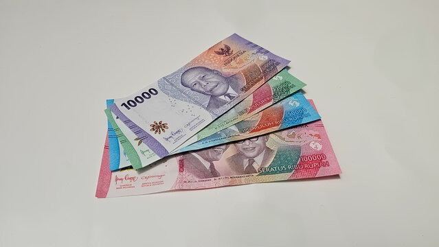 A pile of Indonesian Rupiah banknotes of various denominations stacked on a white background, representing finance, economy, investment, and wealth.