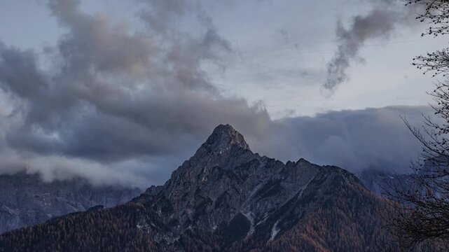Timelapse tra prima e dopo il tramonto, in un ambiente naturale di montagna con cielo nuvoloso, in autunno