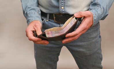 Close up of man opening wallet full of banknotes, representing personal finance, savings cash economy. income control and finance management. full purse of money in Male hands on white background.