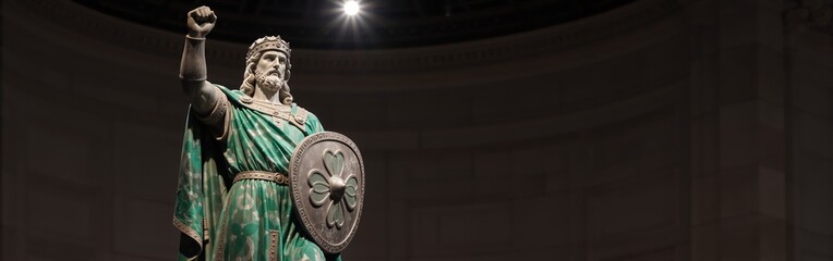 Obraz premium Majestic warrior statue in ornate armor with shield and crown under spotlight