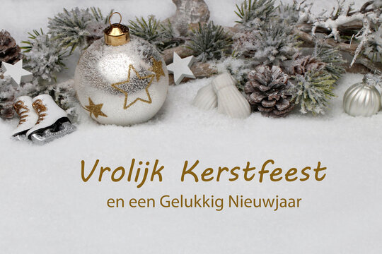 Kerstkaart: Winterlandschap met kerstversieringen en dennentakken in de sneeuw. De Nederlandse groet "Vrolijk Kerstfeest en een Gelukkig Nieuwjaar" is in de sneeuw geschreven.
