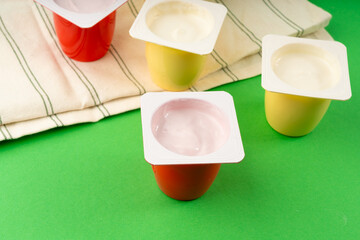 Yogurt cups set, pink and yellow fruit yoghurt in plastic pots, milk pudding container with spoon