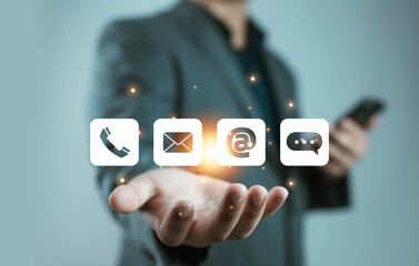 A business person holding floating digital contact icons, including phone, email, and chat symbols, represents modern communication, customer support, online connectivity, and professional service