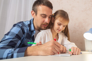 Father, helps his daughter with her homework at home. Homeschooling concept.