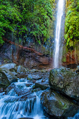 Majestic waterfall in Madeira's lush forest cascades down a rocky cliff, creating a serene stream below. The 25 Fontes or 25 Springs. It's a group of waterfalls located in Rabacal, Paul da Serra