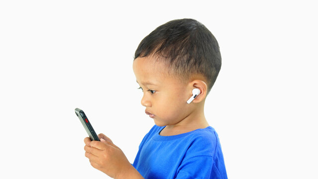 Asian little boy wearing ear buds and holding smartphone listening to children's songs to fill his free time, isolated on white background