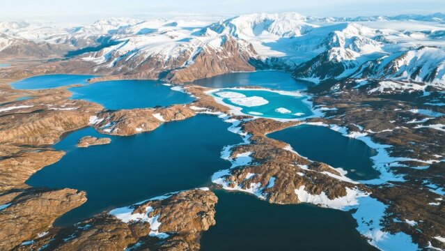 Aerial view of snow-covered mountains and turquoise lakes in a remote Arctic landscape - Powered by Adobe