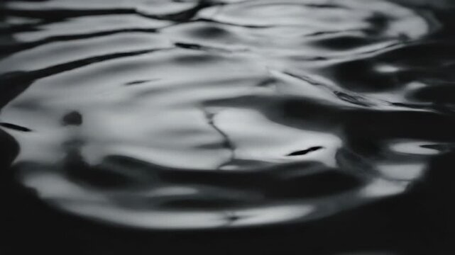 Ultra slow motion visualization of a dark, liquid-like abstract surface being gently rippled and distorted by subtle energy waves tension, mystery, gentlyrippled