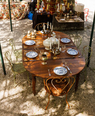 Wooden outdoor table in a garden courtyard set with vintage plates