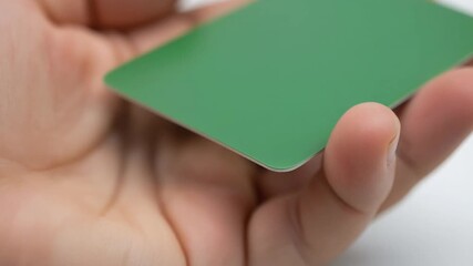 Close-up of a hand holding a blank green card with rounded corners, perfect for business or personal use, adding a touch of color