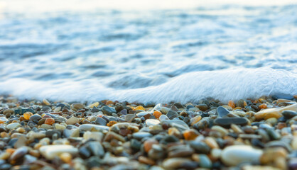 Sea wave rolling over colorful pebbles on the shore