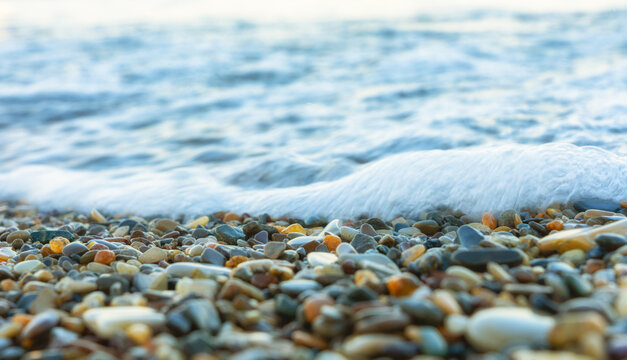 Sea wave rolling over colorful pebbles on the shore