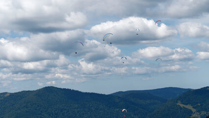 Paragliders Flying Over Mountain Landscape Under Cloudy Sky