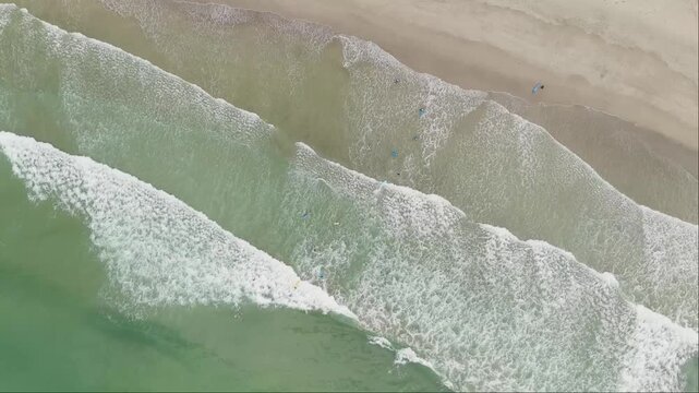 Vista aerea duma praia com ondas a formarem espuma