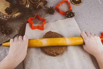 Gingerbread dough and woman hands preparing christmas biscuit cakes.