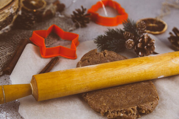 Christmas lifestyle with gingerbread cookies, dough and flour on dark background. Top view. Free space. Flat lay.