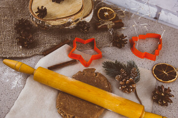 Making gingerbread cookies, Christmas holiday tradition. Raw gingerbread dough with gingerbread man shape and festive metal cutters on rustic table.