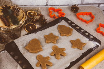 Christmas lifestyle with gingerbread cookies, dough and flour on dark background. Top view. Free space. Flat lay.