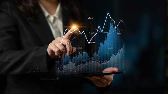 A business professional uses a digital tablet to analyze stock market trends and financial data graphics in a modern workspace setting, showcasing expertise and technology. Scalp - Powered by Adobe