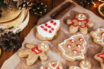 Christmas gingerbread cookies with icing in plate on festive rustic table with decorations, fir branches, golden illumination. Merry Christmas! Delicious gingerbread cookies, atmospheric time