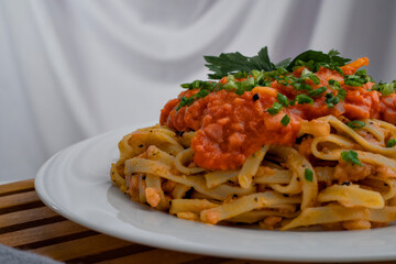 Close up of a plate of spaghetti topped with tomato sauce mixed with meat, cheese, spices, onions and lettuce leaves.