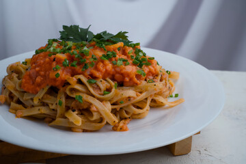 A plate of spaghetti topped with tomato sauce mixed with meat, cheese, spices, onions and lettuce leaves stands on a wooden tray.