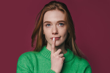 Fototapeta premium redhead woman pondering with finger near lips, fashion portrait
