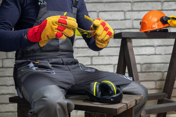 Construction Worker In Uniform Putting on Protective Glasses. Concept of  Personal Protective Equipment on Worksite.