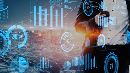 A business professional stands with a smartphone surrounded by glowing financial graphs and data overlays set against a vibrant city skyline at sunset. Xenic