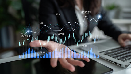 A business professional analyzes financial data on a desk, with digital graphs and charts displaying market trends and statistics in a modern office environment. Scalp