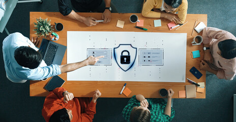 A diverse team engages in a collaborative office meeting focused on cybersecurity and data protection, surrounded by laptops, notes, and coffee cups. Trope