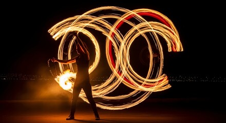 Long exposure photography of a fire poi artist creating circular light trails in the dark. Performer spinning burning equipment at night.