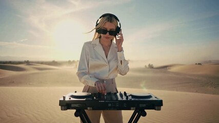 A stylish blonde DJ performs on a sleek mixer in a sunlit desert, warm sand and haze surrounding her as golden light and vibrant tones create a cinematic, summery electronic vibe.