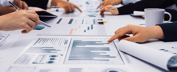 A collaborative business meeting featuring diverse hands engaged in the analysis of data charts and graphs on a table. Professionals collaborate on strategies and insights. SACTR