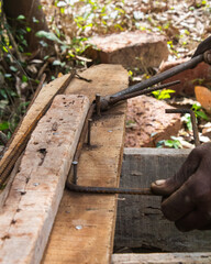 Worker Shaping Steel Rod Using Lever Tool on Wooden Bench