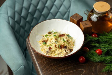A beautifully presented bowl of pasta featuring fresh herbs and savory ingredients sits on a rustic wooden table. Cherry tomatoes and dill enhance the inviting ambiance of the space