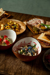 A colorful array of dishes lies on a polished wooden table, showcasing fresh ingredients and comforting flavors in a warm, inviting setting perfect for sharing