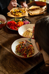 A diverse array of colorful dishes fills the table as friends enjoy a joyful meal together. Laughter and conversation fill the warm atmosphere, creating lasting memories