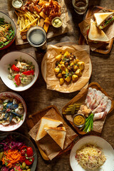 A colorful spread features plates filled with various dishes including salads, sandwiches, and fried foods, capturing the essence of a lively outdoor meal shared among friends