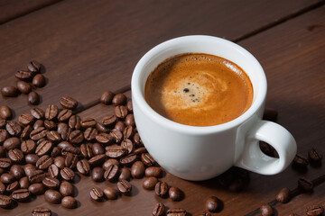 Fresh tasty espresso cup of hot coffee with coffee beans on dark background