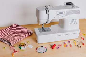 A Modern Sewing Machine with Fabric, Tools, and Supplies for Creative Crafting and Tailoring Projects on a Wooden Table