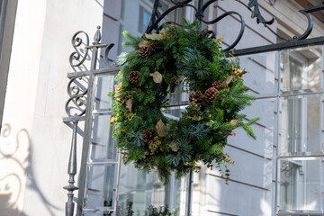 Festive Christmas wreath on window decorated with Christmas lighting, balls, Christmas trees with...
