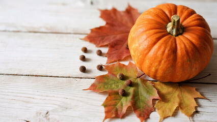 Pumpkin with autumn leaves on wooden surface