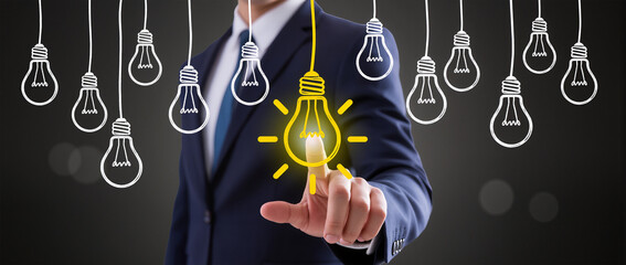 A creative business concept image of a person pointing at a glowing illustrated light bulb among several sketched hanging light bulbs