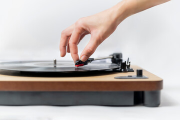 Hand delicately lowering needle onto vinyl record on wooden turntable, retro analog listening moment.
