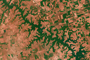 Aerial view of a landscape with green forests and reddish brown fields