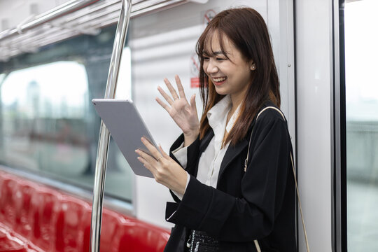 Young Asian businesswoman having a video call on digital tablet while commuting by train. Concept of remote work, digital communication, modern lifestyle and professional mobility. - Powered by Adobe