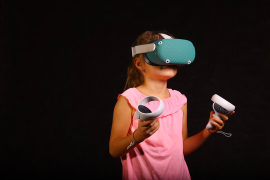 little girl with VR headset and controllers in hands exploring virtual reality as a learning tool and gaming device of the modern era - Powered by Adobe
